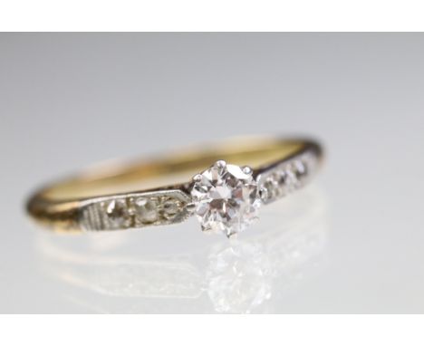18ct gold and platinum diamond ring. The ring being set with a round brilliant cut diamond to the head with further accent di