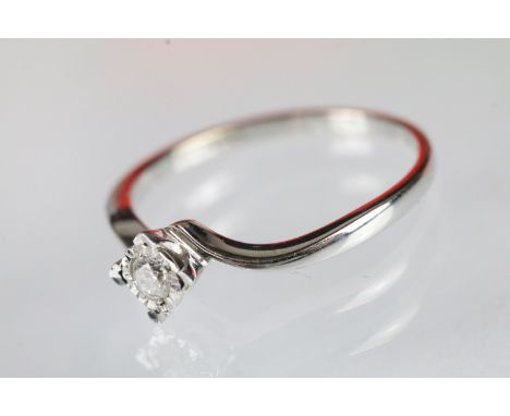 9ct white gold and diamond cross over ring. The ring having a central round cut diamond in cross over shoulders. Hallmarked S