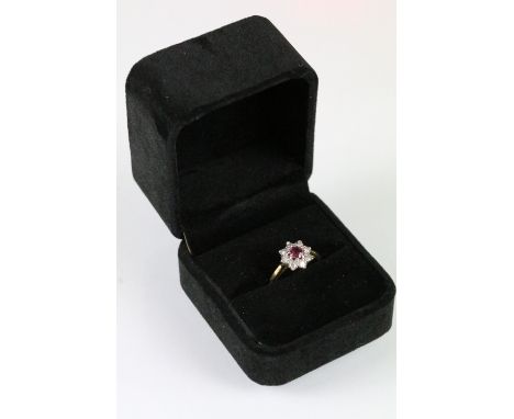 18ct gold ruby and diamond halo ring. The ring being set with a round mixed cut ruby to centre surrounded by single cut diamo