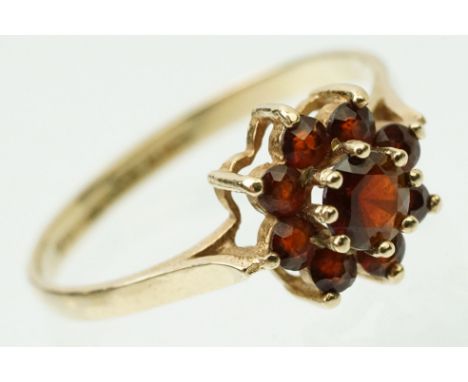 9ct gold and garnet cluster ring set with nine round cut garnets in a flower head design. Hallmarked Birmingham 1976. Size N.