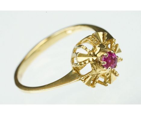Ruby and yellow metal dress ring being set with a round cut ruby to centre within a pierced geometric head. Tests indicate 18