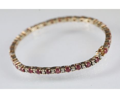 14ct gold ruby and diamond line bracelet being set with round cut rubies in prong settings with diamond accent stones. Marked