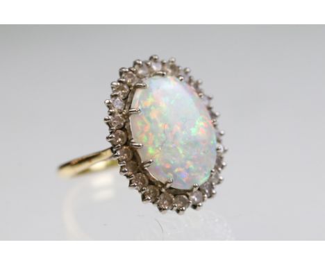 18ct gold, opal and diamond dress ring. The ring being set with a oval opal panel to centre surrounded by a halo of round bri