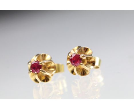 Pair of 18ct gold and ruby stud earrings each being set with a round cut ruby in buttercup settings. Backs marked 18. Rubies 