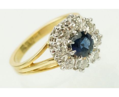 18ct gold sapphire and diamond halo ring. The ring with a round mixed cut blue sapphire to centre with a halo of round brilli