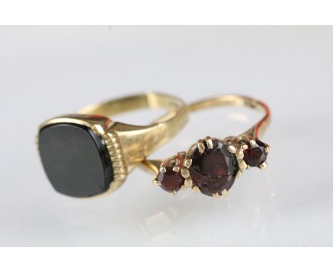 Two 9ct gold rings to include a 9ct gold and garnet three stone ring (AF crack to central stone, hallmarked, size Q), togethe