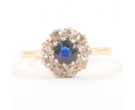 A synthetic sapphire and diamond cluster ring, the circular faceted synthetic sapphire claw set and surrounded by nine early 