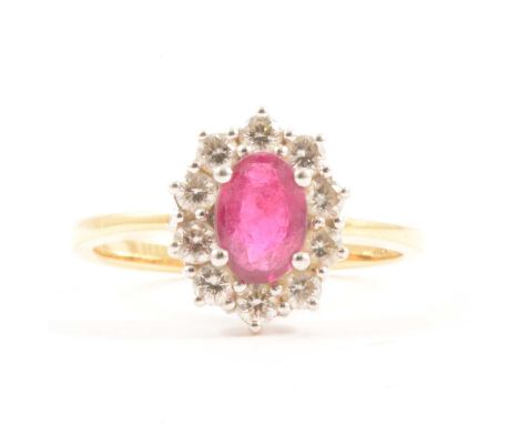 A ruby and diamond cluster ring, the oval mixed cut ruby 7x5mm, four claw set and surrounded by ten brilliant cut diamonds in