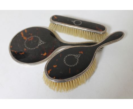 A three piece silver and enamel tortoiseshell backed dressing table brush set 