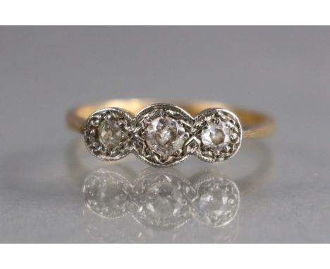 A three-stone diamond ring, the small, graduated stones set to an un-marked yellow metal shank; size: K; 2gm. 