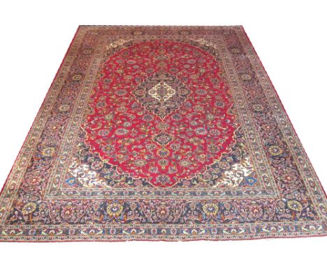 FINE KASHAN CARPET, 400cm x 295cm, of sapphire medallion on ruby field within corresponding bands and borders.