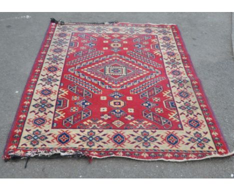 An early 20th century Kazak woollen floor carpet rug. Geometric medallion to centre in large red ground within a beige border