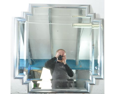 A contemporary Art Deco style wall hanging mirror. The mirror having a stepped edge, with chrome style cushion frame. Featuri