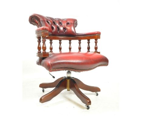 A late 20th century red faux leather Chesterfield button back captains desk chair / swivel armchair. The chair raised on a sp