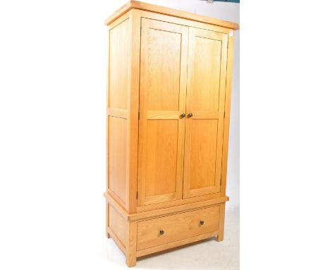 A contemporary Oak Furniture Land manner oak wood wardrobe. The wardrobe raised on block feet, having a single drawer to lowe