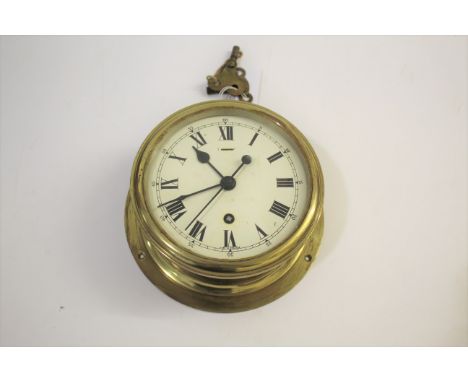 NAVAL BRASS SHIPS CLOCK a bulkhead clock with brass case and fusee movement, the white enamel dial of 15cms diameter. Marked 