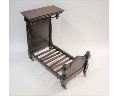 VICTORIAN DOLLS HALF TESTER BED made in mahogany with a canopy headboard at one end, with brass and ceramic castors. 42cms hi