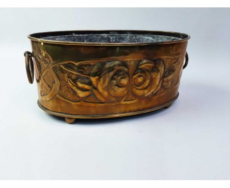 GLASGOW SCHOOL, ARTS & CRAFTS BRASS PLANTER, CIRCA 1900 of oval form with twin hoop handles, embossed with opposing roses ove