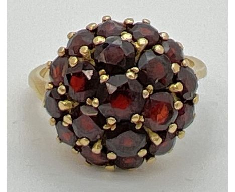 A vintage 18k gold garnet set cluster style ring. Central garnet surrounded by 6 round cut garnets and another 12 smaller siz