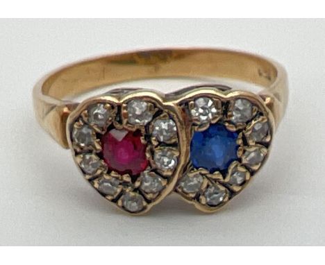 An 18ct gold, ruby, sapphire and diamond ring in a double heart shaped setting. Central round cut ruby and sapphire each surr