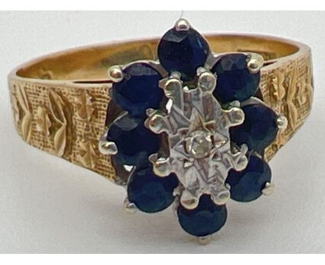 A vintage 9ct gold, sapphire and diamond ring with textured shoulders with floral design. Central illusion set diamond surrou