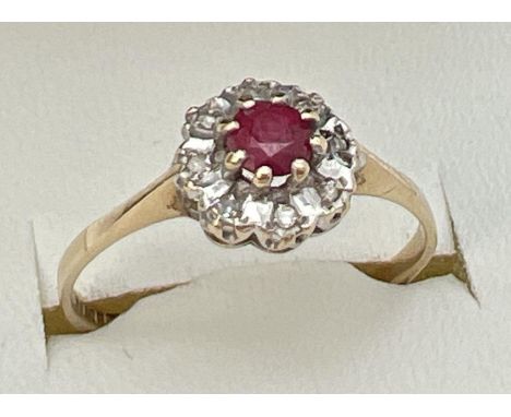 A 9ct gold ruby and diamond ring in a halo style setting. Central round cut ruby surrounded by 8 illusion set diamonds. Fully