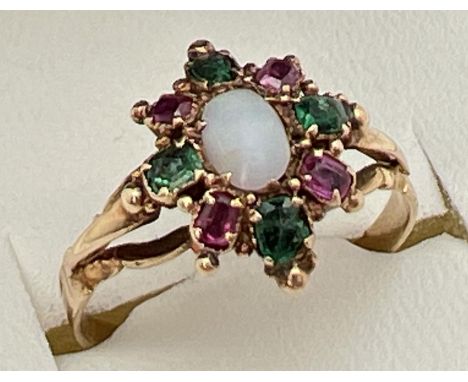 A vintage yellow metal, opal, ruby and emerald ring, unmarked but tests as 9ct gold. Central oval opal cabochon haloed by alt