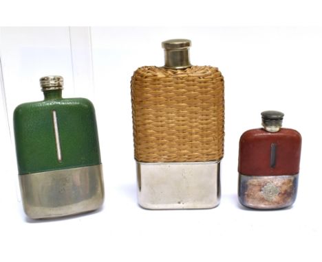 A GLASS HIP FLASK with wicker casing, 18cn high, and two smaller flasks with green and tan leather covering 14.5cm and 10.5cm