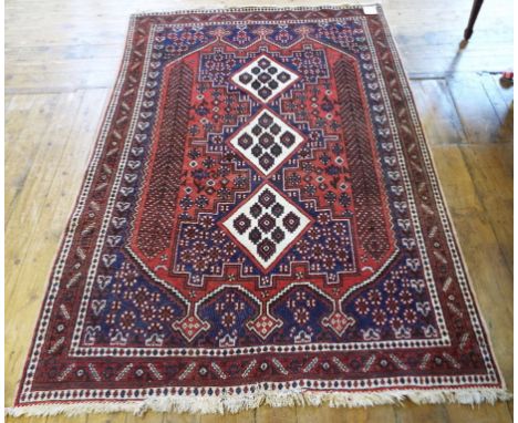 A Persian rug, decorated geometric motifs, on a red ground, 204 x 143 cm