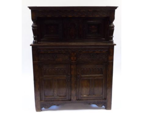 A 17th century style oak court cupboard, with carved decoration, the top section with two panel doors above two frieze drawer