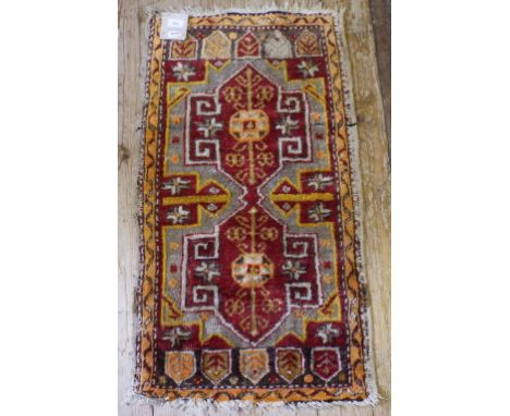 A Persian rug, with geometric motifs, on a red ground, 90 x 51 cm