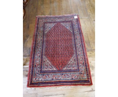 A Persian rug, decorated geometric motifs, on a red ground, 150 x 103 cm
