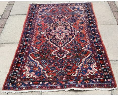 A Persian rug, with a central medallion, on a red ground, 151 x 97 cm