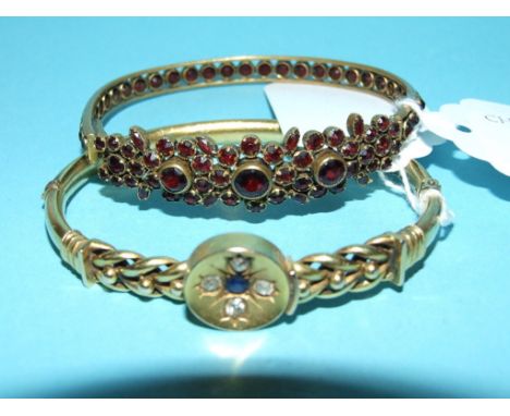A 19th century gilt metal and garnet bangle, and a yellow coloured metal bangle set a sapphire and four diamonds (a.f.) (2) C