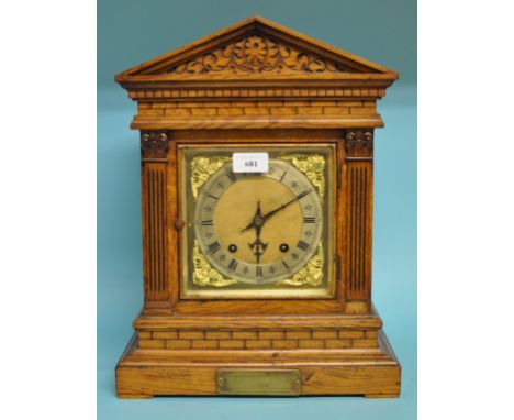 A mantel clock, the 15 cm wide brass dial with Roman numerals, in an architectural style oak case, 41 cm high
