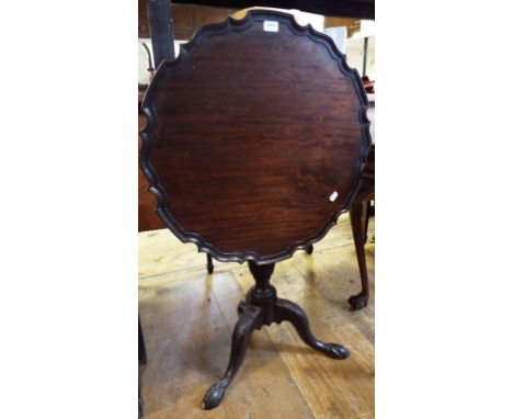 A George III style mahogany tripod table, the pie crust top on a leaf carved baluster column, and leaf carved tripod base wit