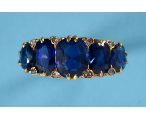 A yellow coloured metal and five stone sapphire ring, the cushion cut stones set with eight small diamonds  See illustration