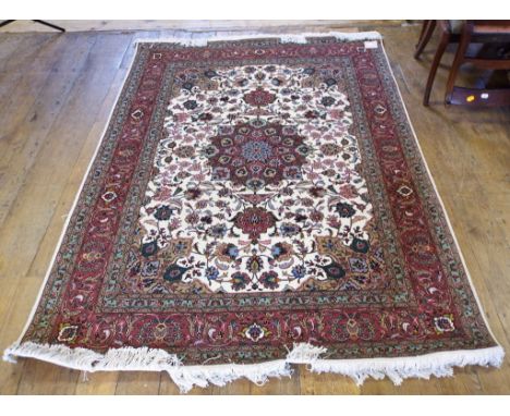 A Persian Tabriz rug, with a central medallion, on a white ground, within a multi border, 207 x 151 cm, and another similar, 
