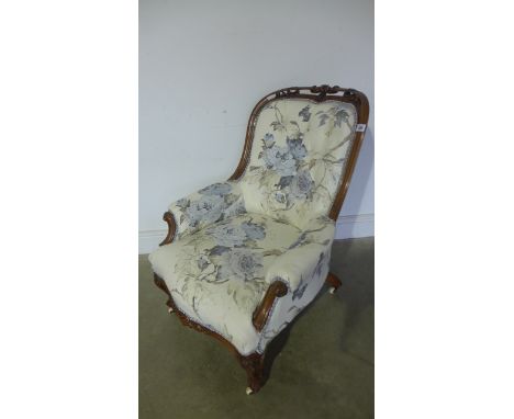 A Victorian walnut carved button back armchair recently re upholstered in a floral material