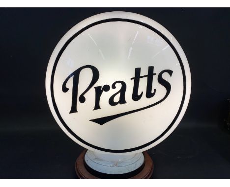 A reproduction Pratts glass petrol pump globe, mounted on a wooden stand. 