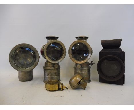 Three nickel plated carbide lamps, a brass bicycle bell, a brass cased voltmeter and a rear lamp.