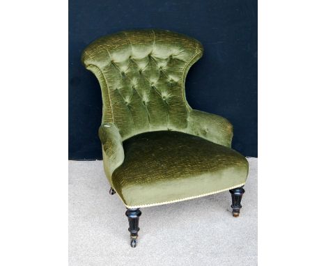 Victorian button-back nursing chair with stuff-over seat, raised on fluted ebony baluster turned legs terminating in ceramic 