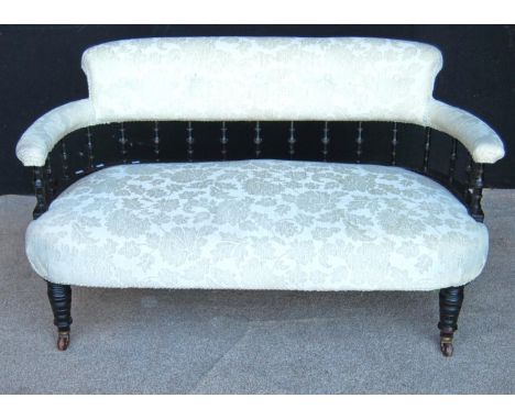 Late Victorian parlour sofa with cushioned top rail over balustrade, stuff-over seat and raised on ring turned legs terminati