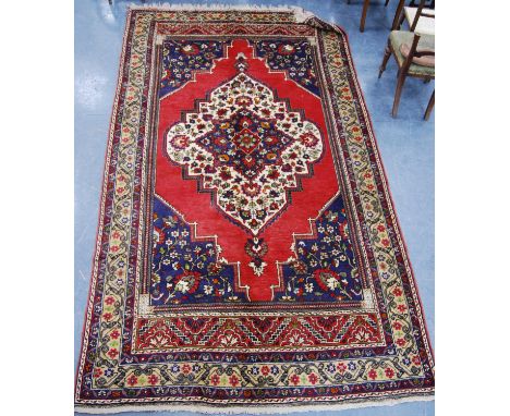 Turkish carpet with central floral medallion over red ground, blue floral spandrels and floral border, 355cm x 200cm. 