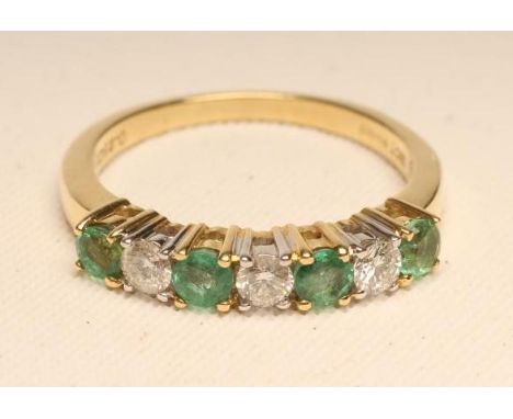 AN EMERALD AND DIAMOND HALF HOOP ETERNITY RING, the four circular facet cut emeralds and three brilliant cut diamonds point s