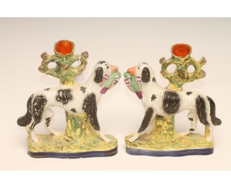 A PAIR OF VICTORIAN STAFFORDSHIRE POTTERY SPILL VASES, modelled as hunting dogs with brightly coloured birds in their mouths,