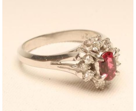 A RUBY AND DIAMOND CLUSTER RING, the oval facet cut (un-heat treated) ruby claw set to a border of twelve small round brillia