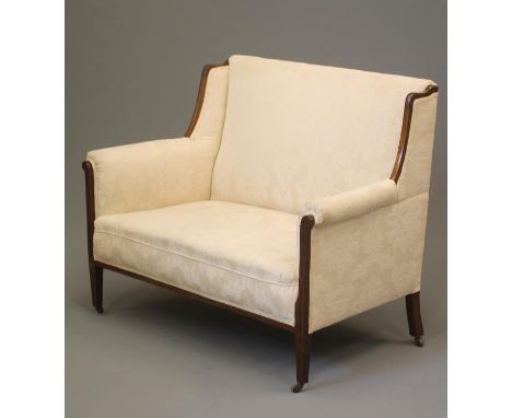 AN EDWARDIAN MAHOGANY FRAMED SOFA of high back form with stringing and upholstered in ivory damask, straight top rail, mildly