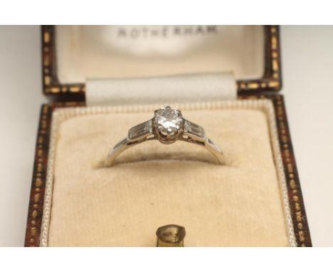 A DIAMOND RING, the central brilliant cut stone of approximately 0.20cts flanked by a pair of smaller horizontal set baguette