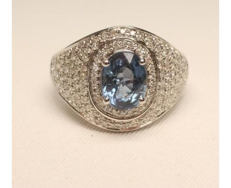 A SAPPHIRE AND DIAMOND COCKTAIL RING, the oval cut sapphire of approximately 2.60cts claw set to a domed panel millegrain set